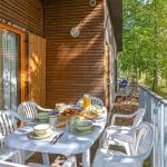 Slide Terrasse aménagée d’un cottage en bois au Valjoly avec table dressée pour le petit-déjeuner en pleine nature