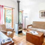 Slide Salon d’un cottage 3 pièces pour 6 personnes au Valjoly avec canapé, fauteuil, poêle à bois et terrasse donnant sur la nature