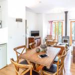 Slide Salon d’un cottage 3 pièces pour 6 personnes au Valjoly avec sallle à manger avec tables et chaises canapé, fauteuil, poêle à bois et terrasse donnant sur la nature