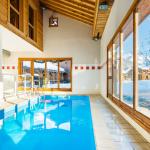 Slide Piscine intérieure lumineuse avec grandes baies vitrées donnant sur la neige aux Fermes de Samoëns.