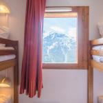 Slide Sleeping area with bunk beds and a window overlooking the snow-covered mountains in the Les Etoiles d'Orion residence.