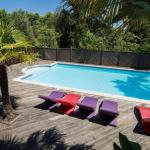 Slide General view of the swimming pool with sun loungers and palm trees at the Les Collines Iduki residence