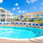 Slide Outdoor pool area surrounded by sun loungers and lush green gardens at the L’Estran residence in Les Sables-d’Olonne
