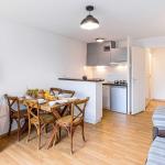 Slide Open-plan kitchen with a worktop overlooking the living area with sofa and television in the apartments of the Les Rives Marines residence in Le Teich