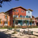 Slide Wood-clad, colourful buildings arranged in a row, with a pétanque court and bicycle rack at the Les Rives Marines residence in Le Teich