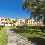 Slide Mediterranean-style residence with lush gardens featuring olive trees, shrubs, and palm trees, and a paved central walkway at the Sognu di Mare residence in Linguizzetta
