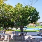 Slide Terrasse avec tables à manger et vue sur la piscine extérieure de la résidence Pedras del Rei