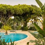Slide Outdoor swimming pool with sun loungers and parasols in a tree-lined setting