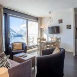 Slide Salon avec coin repas et TV ouvert sur un balcon avec vue sur les montagnes depuis les appartements Les Terrasses de Veret à Flaine