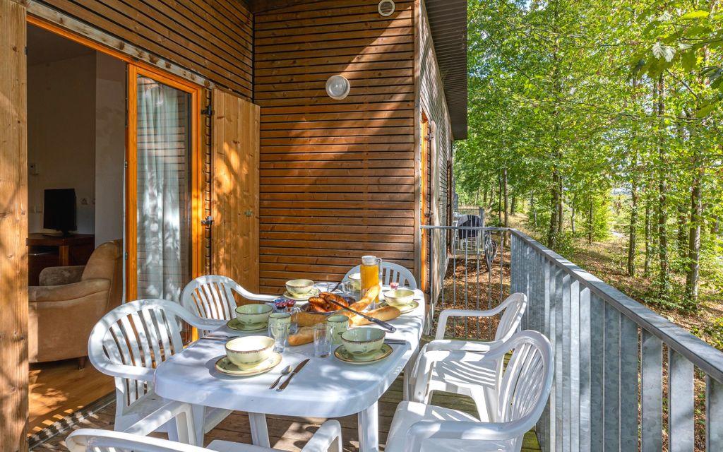 Slide Terrasse aménagée d’un cottage en bois au Valjoly avec table dressée pour le petit-déjeuner en pleine nature