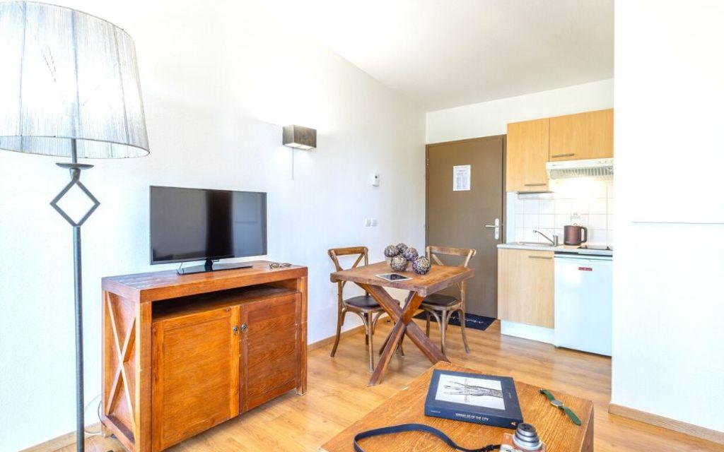 Slide Intérieur d’un cottage au Valjoly avec coin cuisine équipé, table en bois et télévision dans le salon