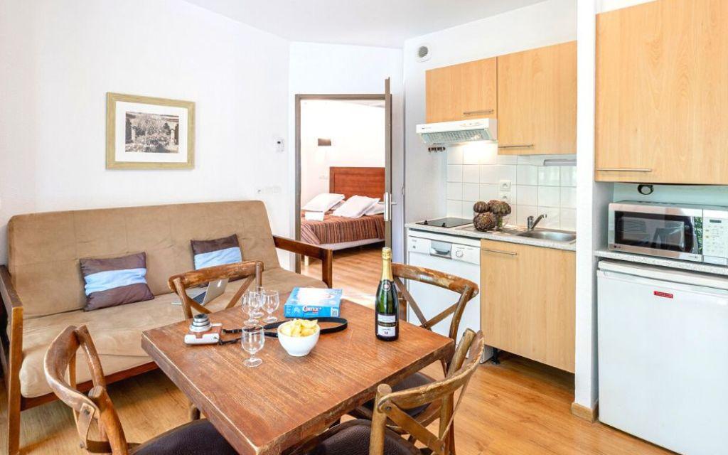 Slide Intérieur d’un cottage au Valjoly avec canapé, coin repas et cuisine équipée, donnant sur une chambre double