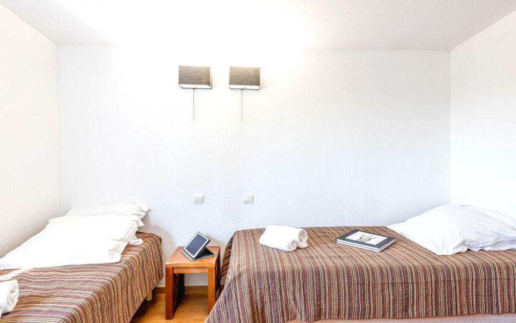Slide Chambre d’un cottage 4 pièces 8 personnes au Valjoly avec deux lits simples séparés et table de chevet