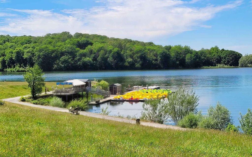Slide Pédalos colorés amarrés sur le lac de Valjoly, au cœur d’un cadre naturel verdoyant idéal pour les activités nautiques