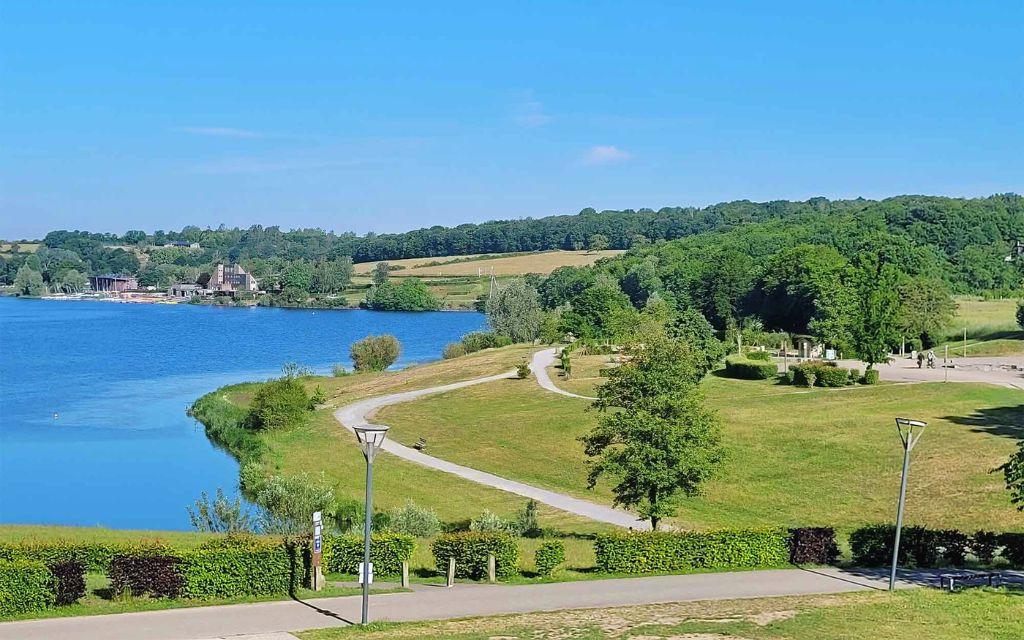 Slide Vue sur le lac de Valjoly et ses berges aménagées avec sentiers de promenade et espaces verts pour des balades en pleine nature