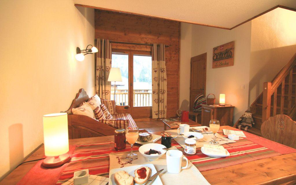 Slide Séjour cosy aux Fermes de Samoëns avec table dressée pour le petit-déjeuner et canapé en bois.