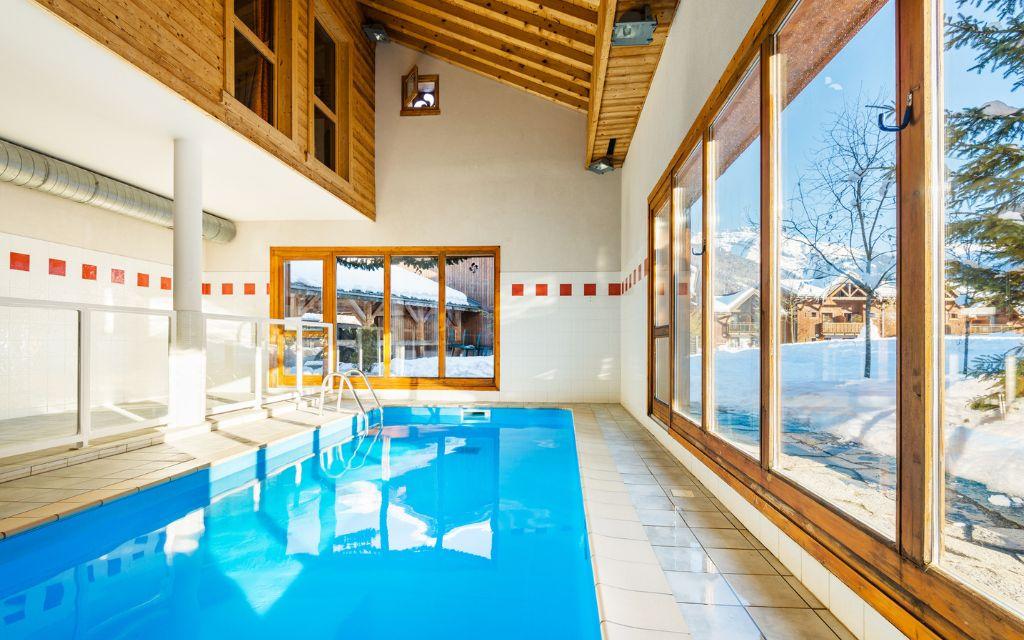 Slide Piscine intérieure lumineuse avec grandes baies vitrées donnant sur la neige aux Fermes de Samoëns.