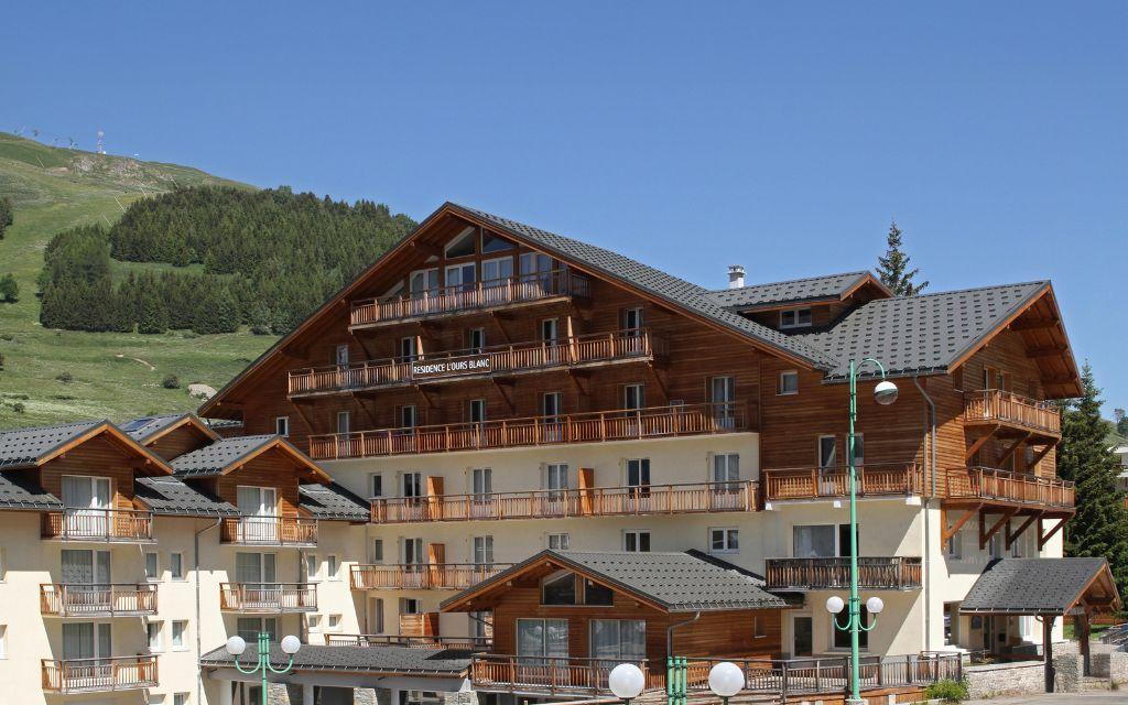 Slide L'Ours Blanc residence in Les Deux Alpes with wooden façade under beautiful sunshine