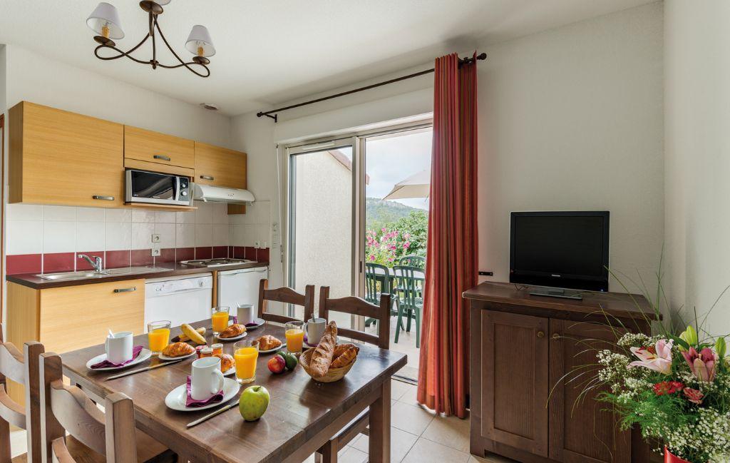 Slide Kitchen and dining room with table set in the Domaine des Cazelles residence