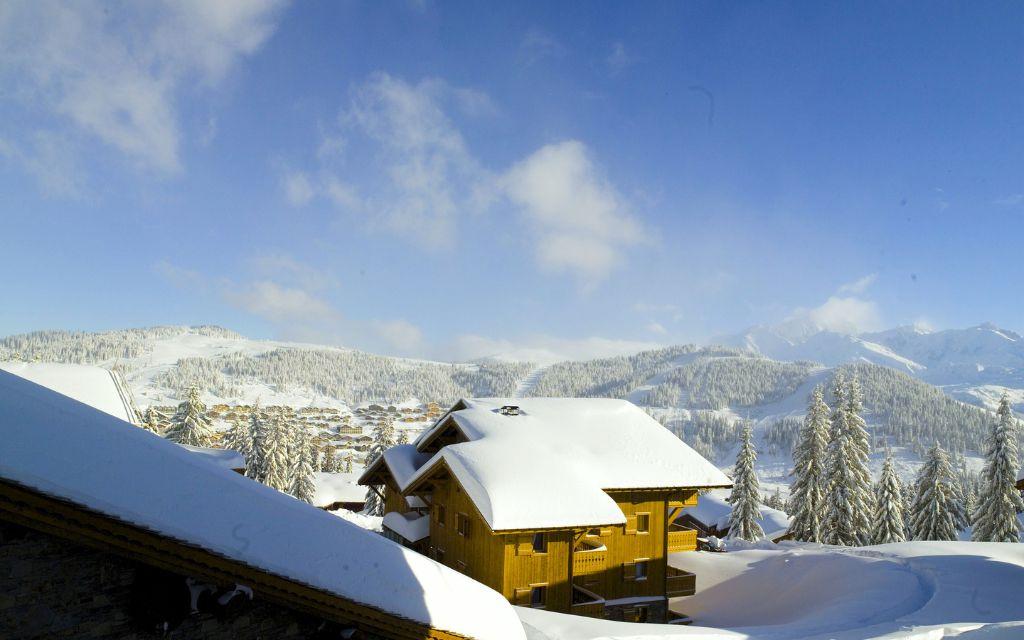 Slide view of the Le Hameau de Beaufortain residence over snow-capped mountains and beautiful sunshine