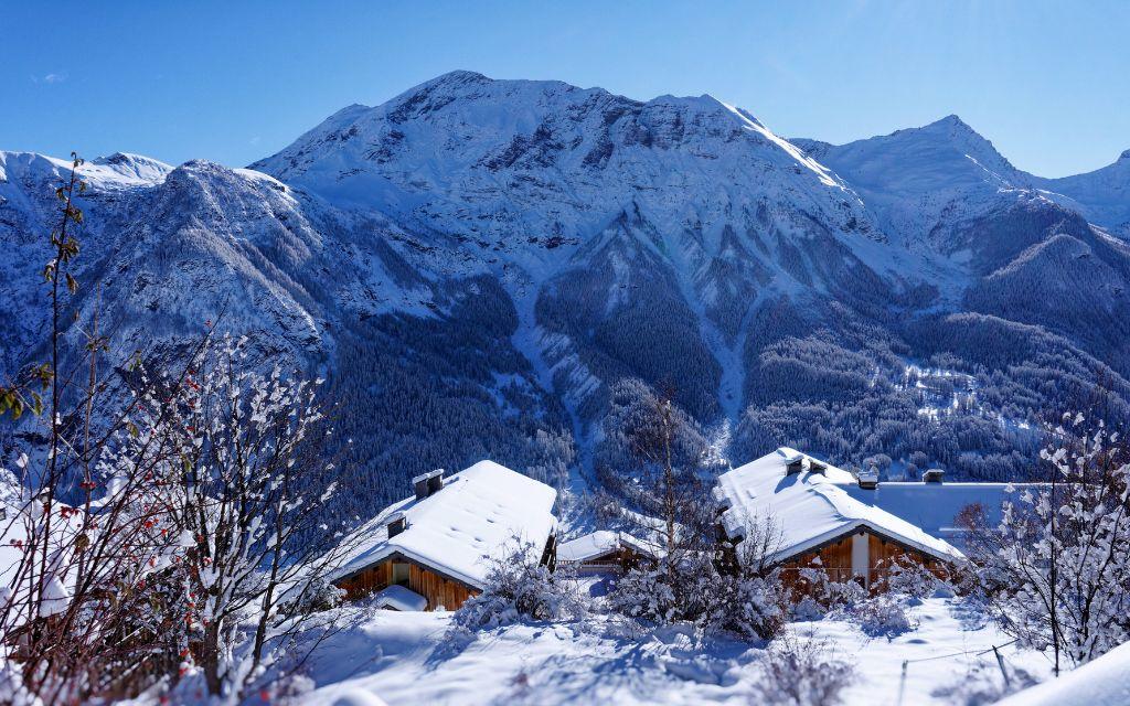 Slide Overall view from behind the Les Etoiles d'Orion residence with mountains covered in snow