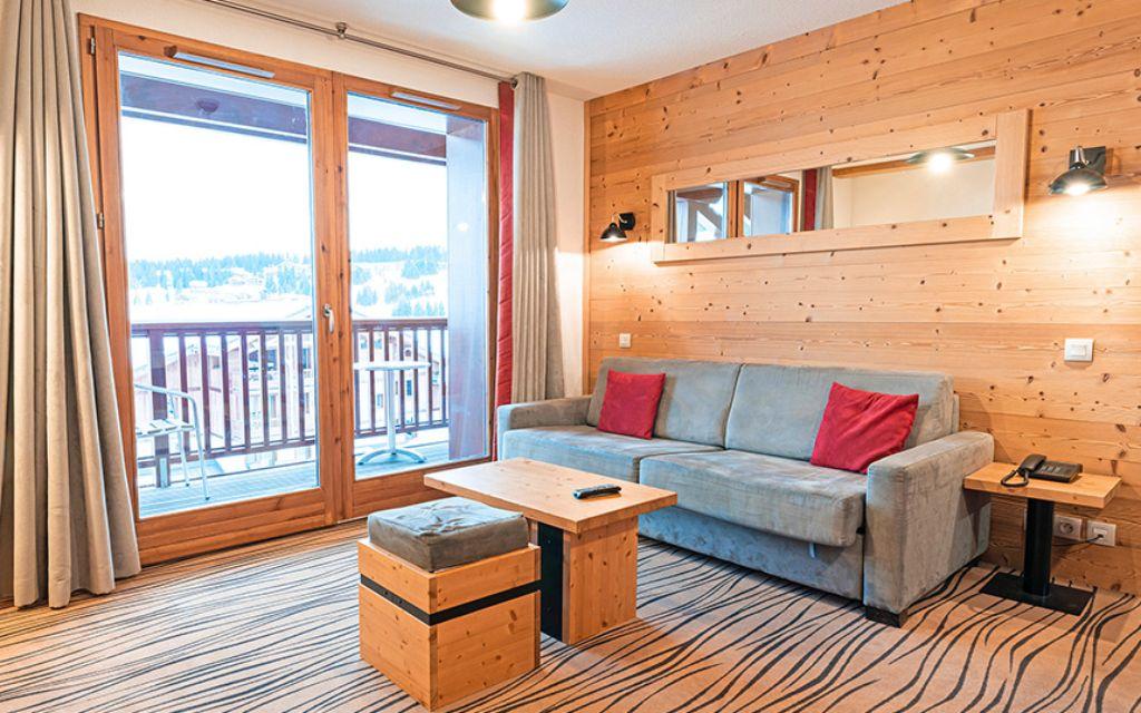 Slide Salon avec canapé-lit et balcon vue sur les montagne aux Chalets d’Emeraude