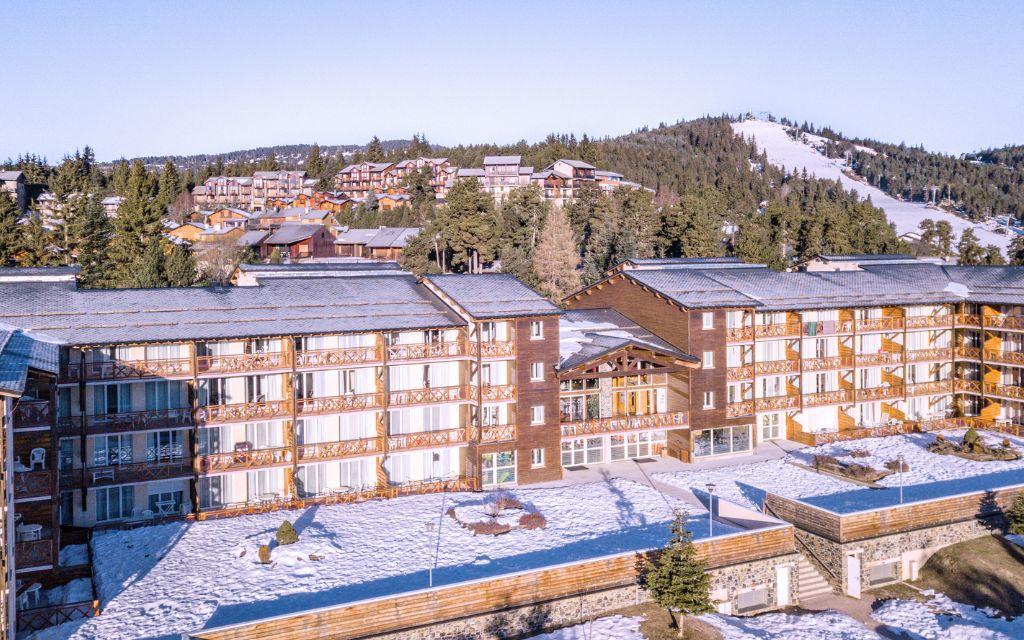 Slide Exterior of the Pyrénées 2000 residence with a mountain in the background, covered in snow in winter