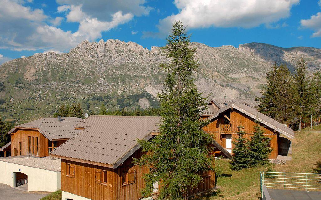 Slide Vue d’ensemble de la résidence L’Orée des Pistes l’été avec vue sur les montagne