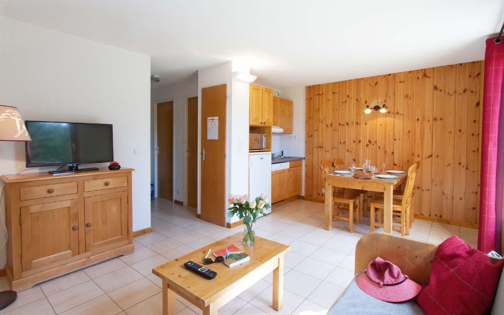 Slide Living room with open kitchen and lounge area with TV at the Résidence L’Orée des Pistes