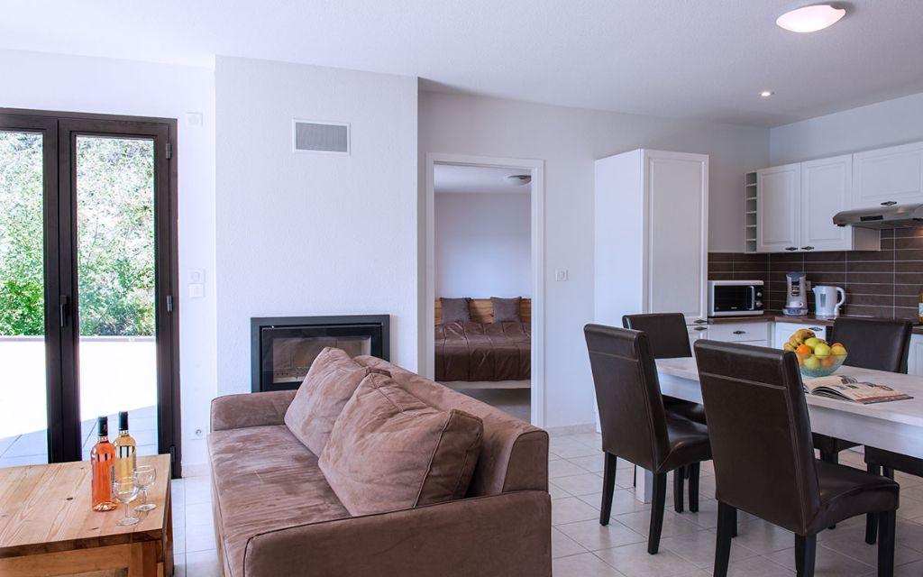 Slide Overview of the living room with sofa and dining table in the apartments at the L’Écrin du Lac estate in Chorges