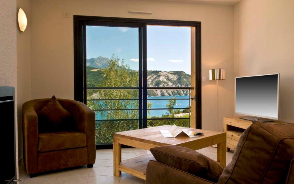Slide Living room with sofa and flat-screen TV with lake view at L’Écrin du Lac in Chorges