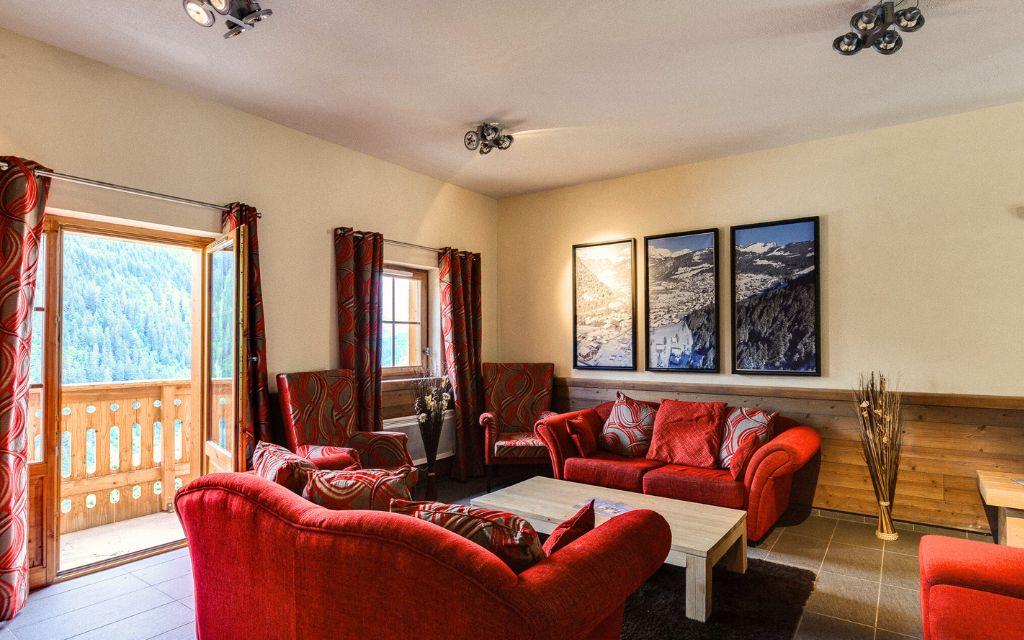 Slide Grand salon avec des canapés rouges et une vue sur les montagne de Châtel