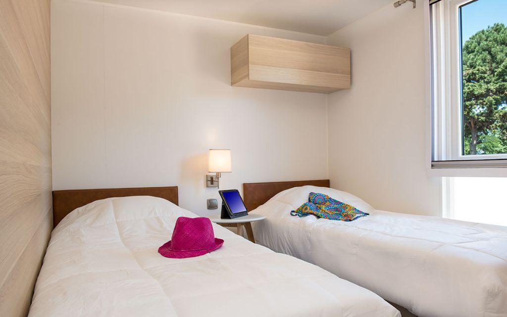 Slide Chambre avec deux lits simples et meuble de rangement en hauteur dans le cottage vip au village vacances Les Mûriers