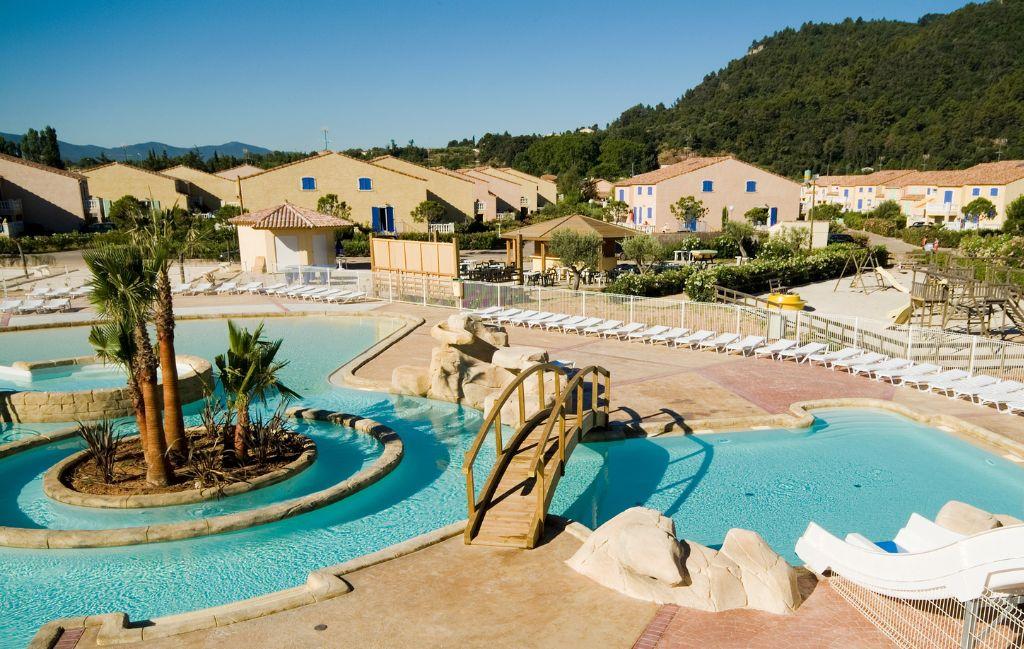 Slide Piscine extérieure de la résidence le clos des oliviers avec transats et pont au-dessus de l’eau