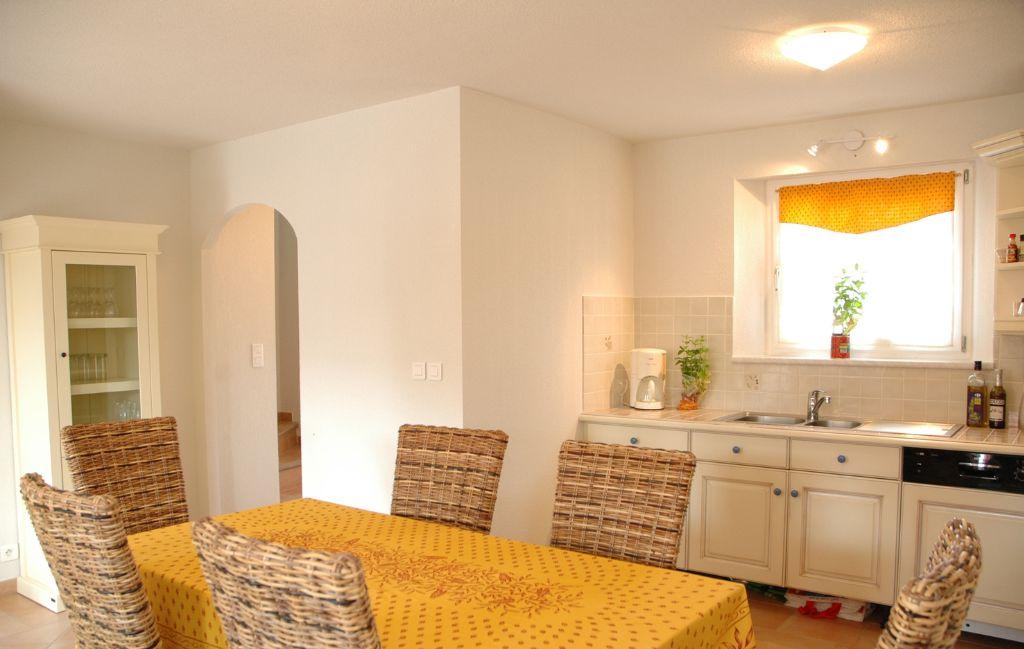 Slide Dining area with table and open kitchen in a house at Le Clos des Oliviers residence
