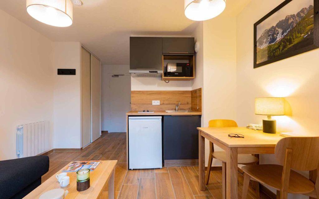 Slide Kitchenette opening onto the living room of a studio apartment at the Arya Living Stone residence in Vars