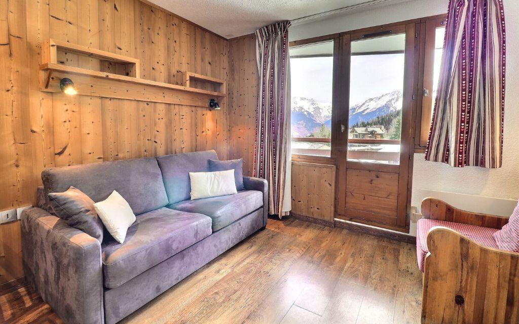 Slide Salon avec canapé-lit et parquet en bois d’un appartement de la résidence Grand Bois à Courchevel La Tania