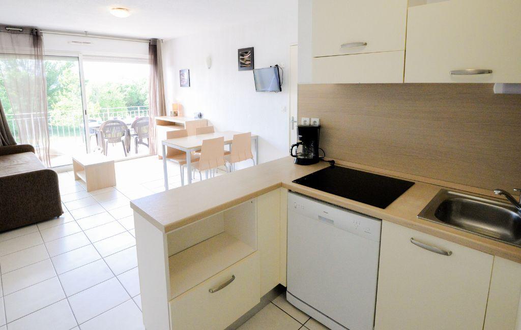 Slide Fully equipped kitchen opening onto the living room of an apartment in the Château de Jouarres residence in Azille