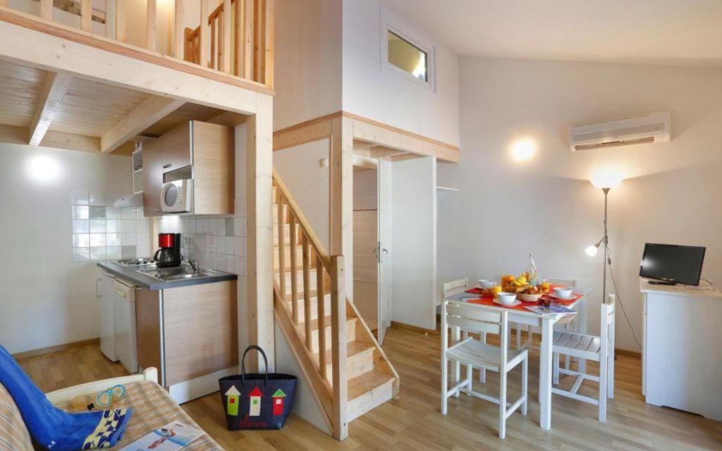 Slide Séjour ouvert sur une cuisine équipée avec TV dans les maisonnettes des Sabees Vignier à Oléron