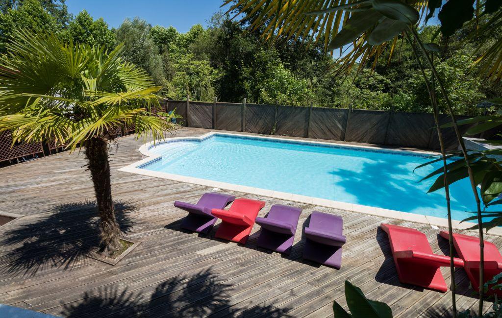 Slide General view of the swimming pool with sun loungers and palm trees at the Les Collines Iduki residence