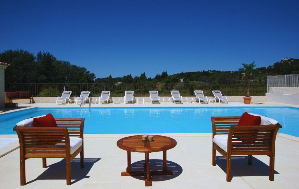 Slide Outdoor swimming pool with sun loungers and garden furniture at the Bourgeac estate near Les Beaux de Provence