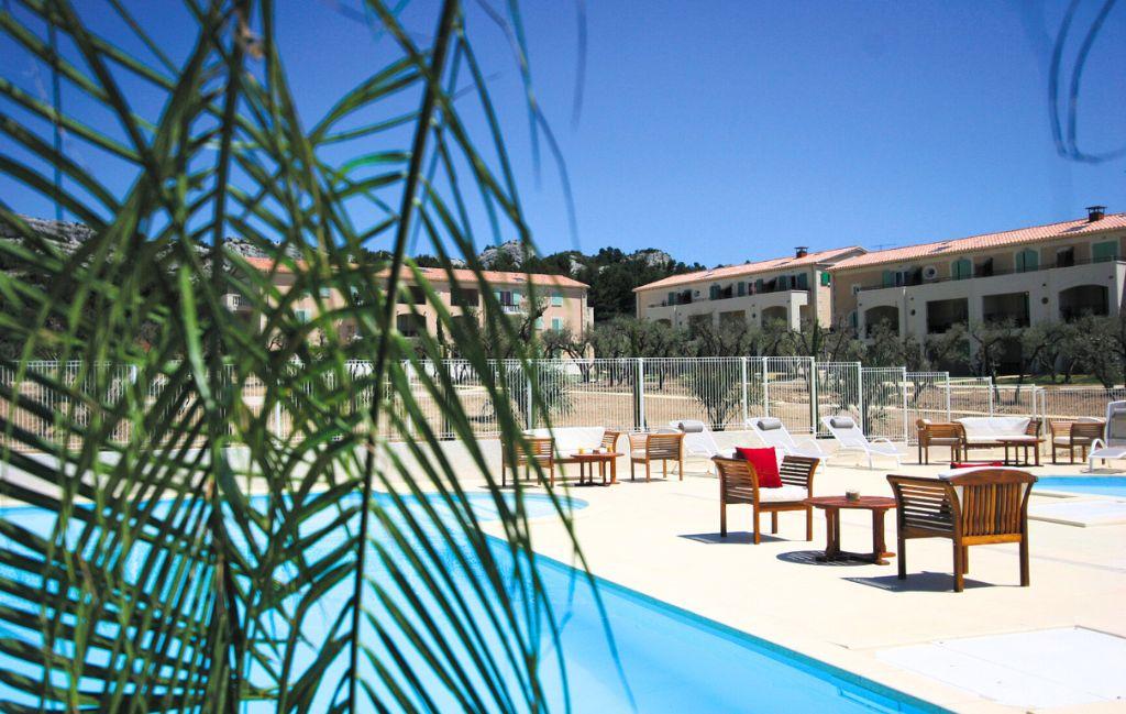 Slide View of the outdoor swimming pool with garden furniture and buildings in the background at the Bourgeac estate