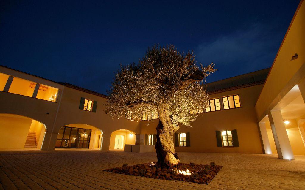 Slide Night view of the patio with its central olive tree, a symbol of Provence, at Domaine de Saint-Endréol Golf & Spa Resort in La Motte-en-Provence