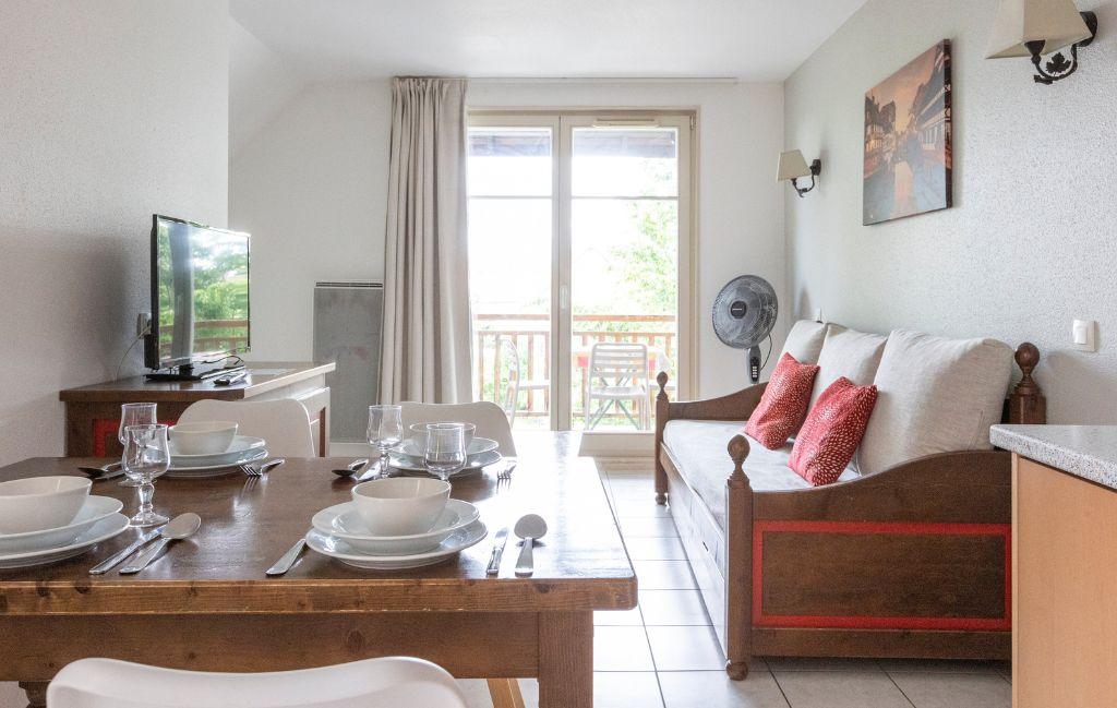 Slide Salon ouvert sur un balcon avec TV et connexion internet dans les logements de la résidence Le Domaine du Rois à Bergheim