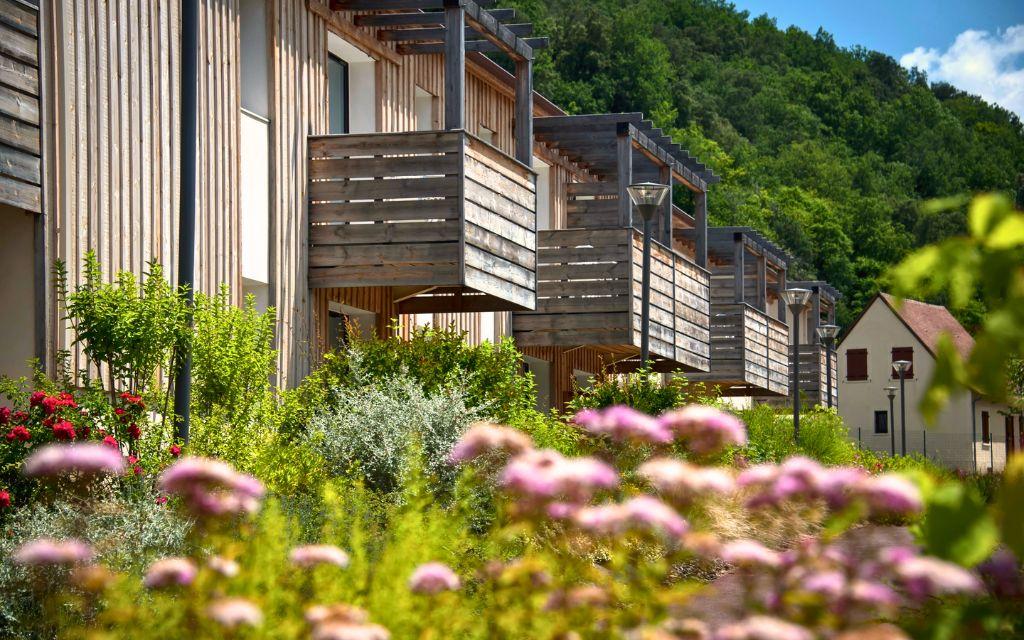 Slide Wooden exterior façades of the accommodations at Résidence Le Clos du Rocher in Dordogne