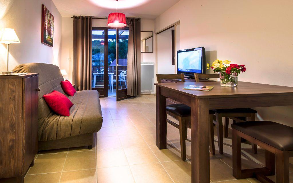 Slide Living area with dining space and lounge in an apartment at Résidence Le Clos du Rocher in Dordogne