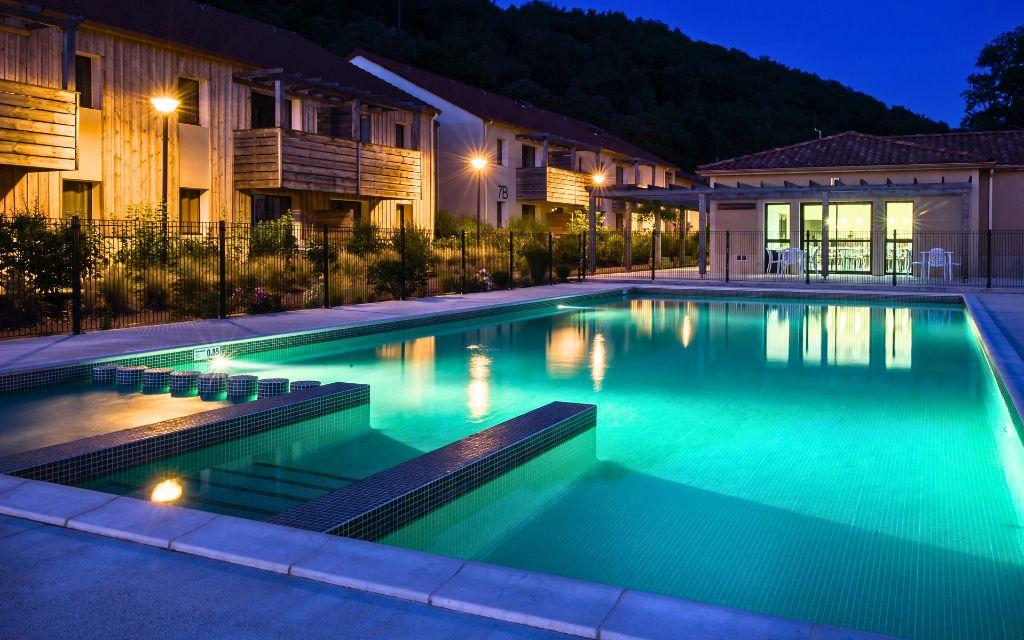 Slide Pool at Résidence Le Clos du Rocher in Dordogne illuminated at night