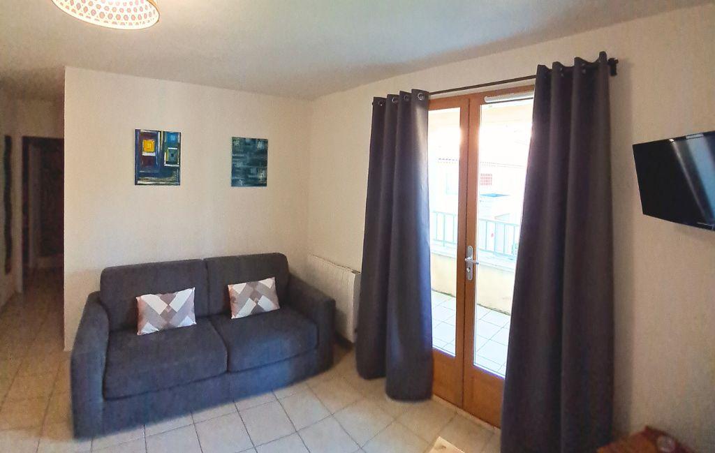 Slide Bright living room with pull-out sofa and television in the apartments of the Le Hameau des Sources residence in Montbrun-les-Bains
