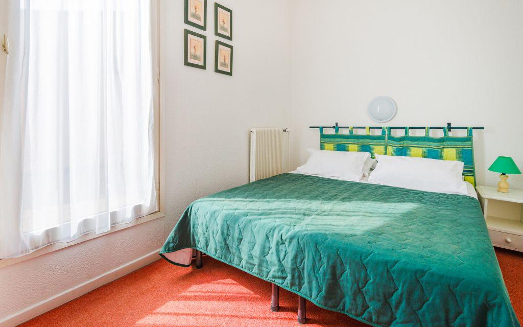 Slide Bedroom with a double bed and bedside table in an apartment at Résidence du Golf
