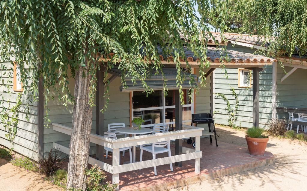 Slide View of a covered terrace with garden furniture and a BBQ in the Premium Bungalows at Camping del Mar 4* in Malgrat de Mar